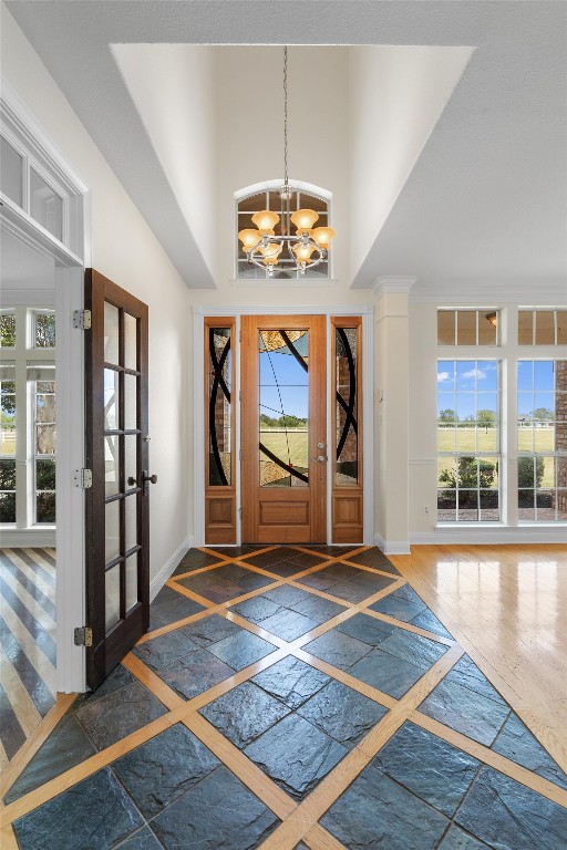 foyer with a notable chandelier, dark hardwood / wood-style flooring, high vaulted ceiling, and a wealth of natural light