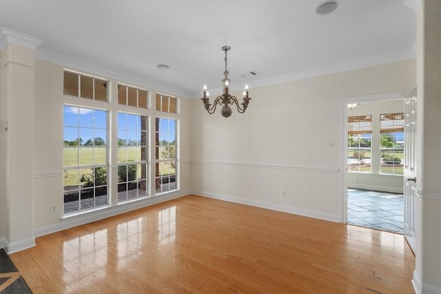 empty room featuring ornamental molding, light wood-type flooring, and an inviting chandelier