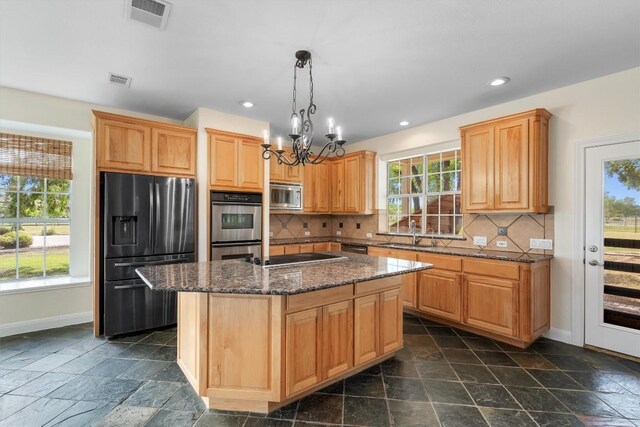 kitchen featuring decorative backsplash, a kitchen island with sink, a chandelier, and stainless steel appliances