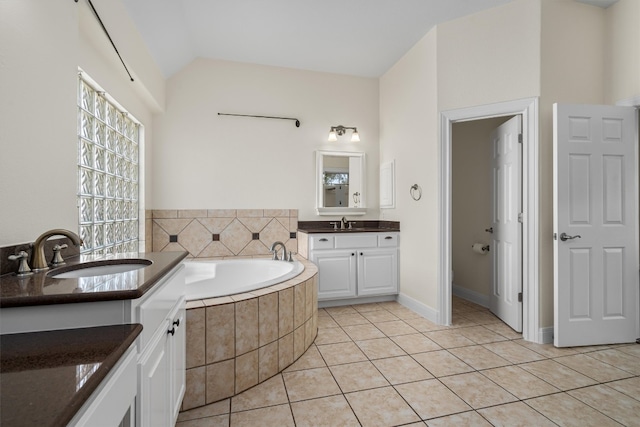 bathroom featuring tiled tub, vanity, lofted ceiling, and tile patterned flooring