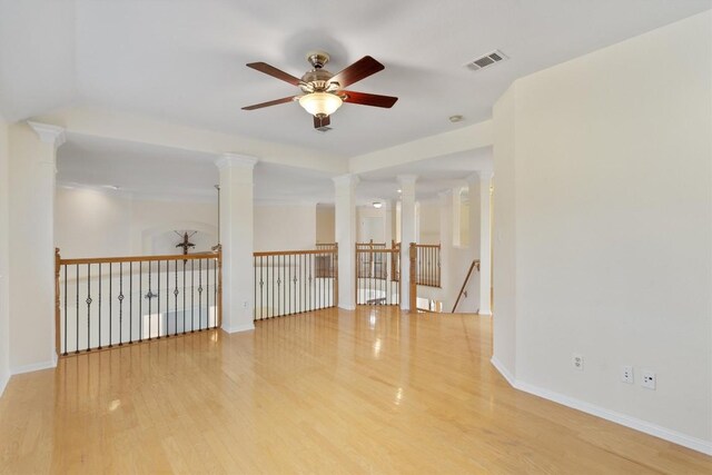 unfurnished room with ceiling fan, hardwood / wood-style flooring, and ornate columns