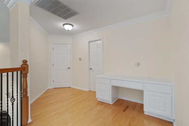 unfurnished office featuring ornamental molding, built in desk, and light hardwood / wood-style floors