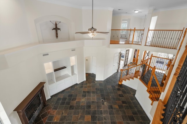 interior space featuring a towering ceiling, ceiling fan, and crown molding