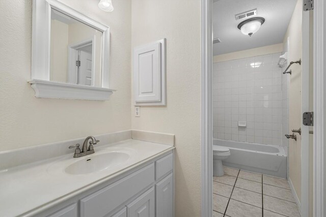 full bathroom featuring tile patterned flooring, vanity, toilet, and tiled shower / bath