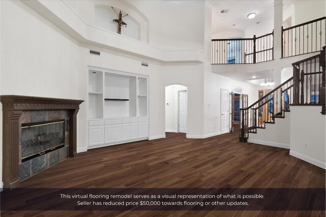 unfurnished living room with built in shelves, a fireplace, wood finished floors, baseboards, and stairway