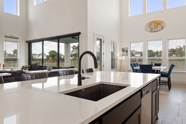 kitchen featuring a towering ceiling, white dishwasher, a wealth of natural light, and sink