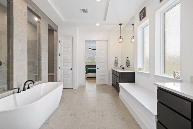 bathroom with vanity, a raised ceiling, ceiling fan, and a healthy amount of sunlight