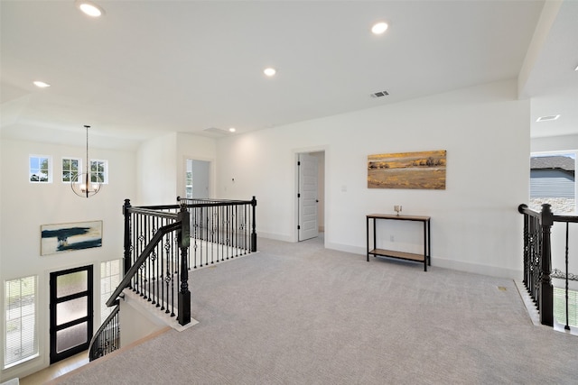 hallway featuring light colored carpet and a chandelier