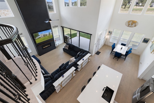 living room with a high ceiling, hardwood / wood-style flooring, and ceiling fan