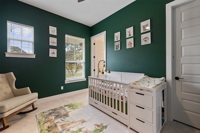 carpeted bedroom with multiple windows and a nursery area