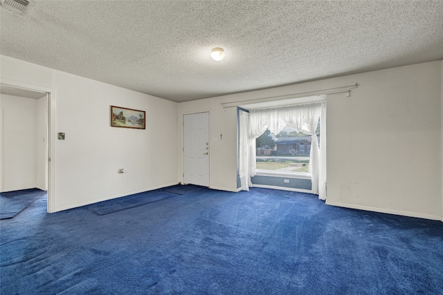 spare room featuring a textured ceiling and dark colored carpet