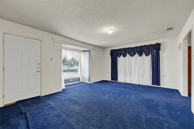 unfurnished room with dark carpet and a textured ceiling