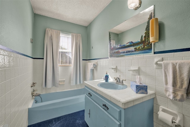 bathroom featuring tile walls, vanity, a textured ceiling, and a washtub