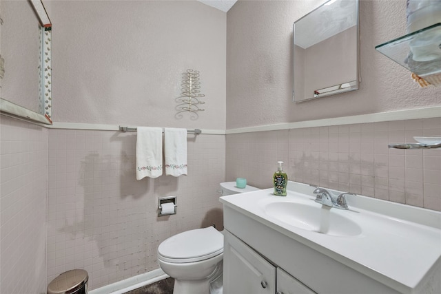 bathroom featuring vanity, tile walls, and toilet