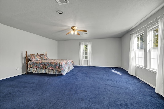 carpeted bedroom featuring multiple windows, a textured ceiling, and ceiling fan