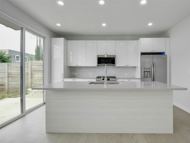 kitchen featuring recessed lighting, stainless steel appliances, a sink, tasteful backsplash, and white cabinetry