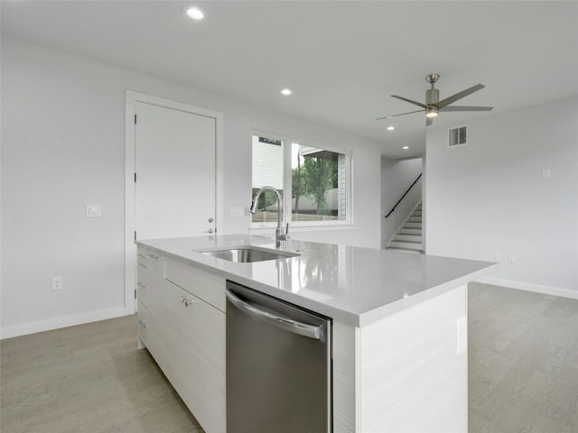kitchen with a sink, an island with sink, light wood-type flooring, dishwasher, and visible vents