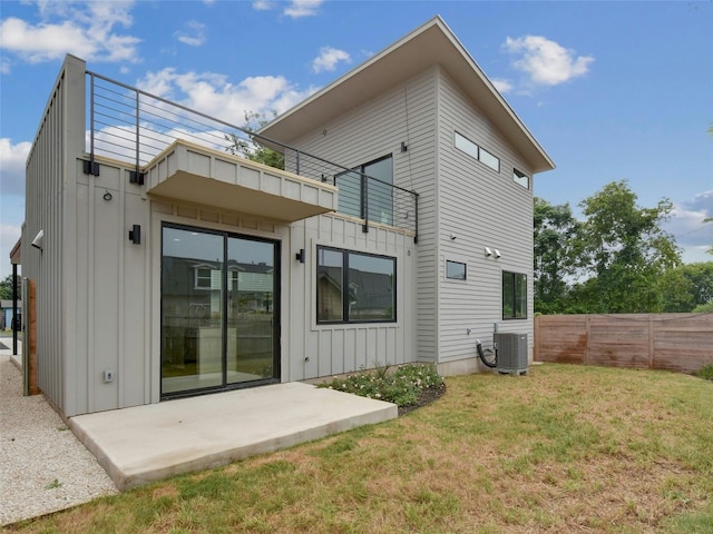 back of property featuring board and batten siding, a balcony, central AC, and a patio