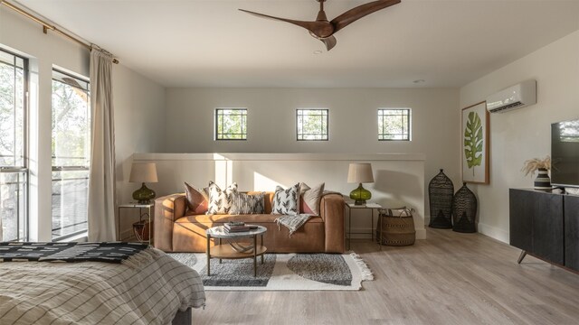 bedroom featuring a wall mounted air conditioner, multiple windows, light wood-type flooring, and ceiling fan