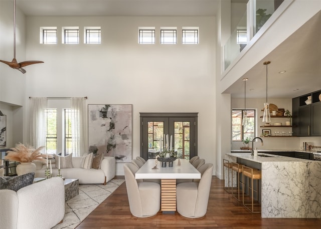 dining space featuring sink, wood-type flooring, and a towering ceiling