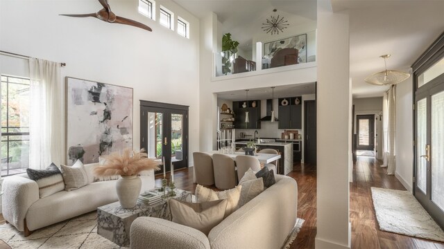 living room with ceiling fan, high vaulted ceiling, wood-type flooring, french doors, and sink