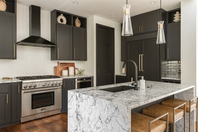 kitchen featuring an island with sink, hanging light fixtures, wall chimney exhaust hood, dark wood-type flooring, and high end appliances