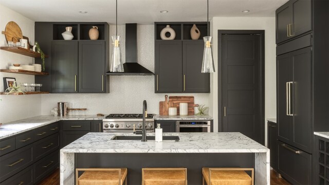 kitchen featuring a kitchen bar, hanging light fixtures, wall chimney range hood, and oven