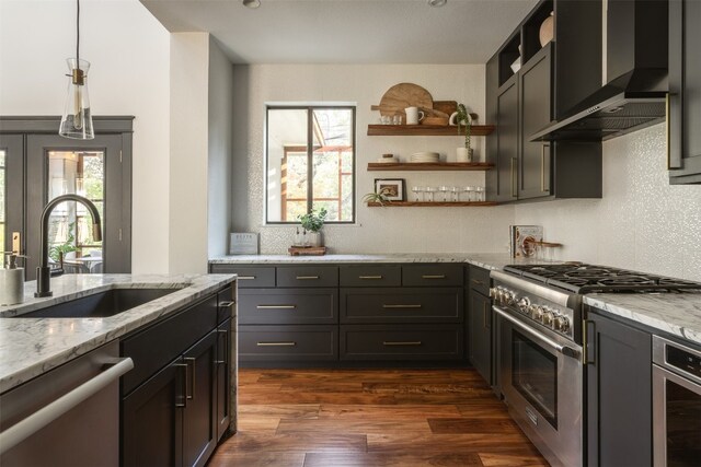 kitchen featuring stainless steel appliances, wall chimney range hood, sink, and plenty of natural light