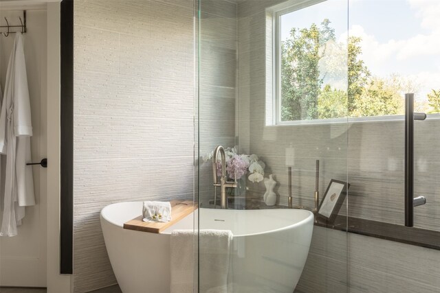 bathroom featuring a bathtub and tile walls