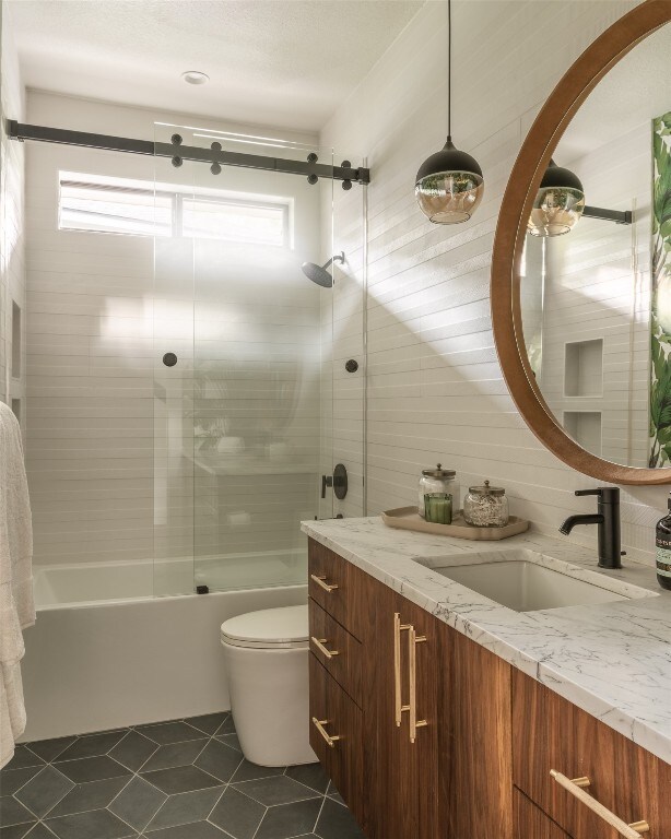 full bathroom featuring vanity, tiled shower / bath combo, toilet, and tile patterned flooring