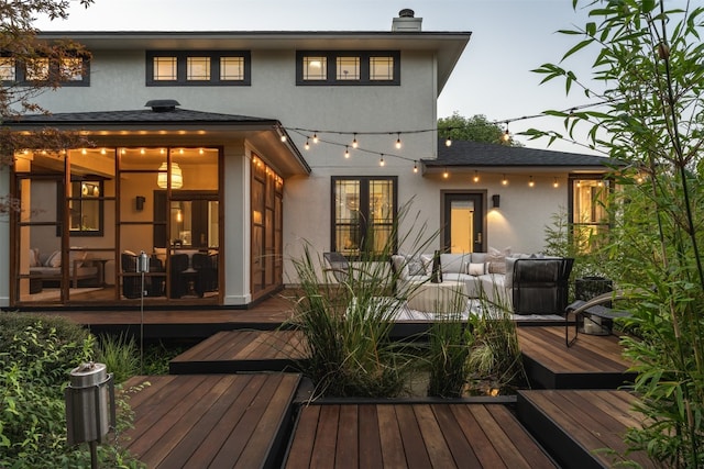 back house at dusk featuring a wooden deck