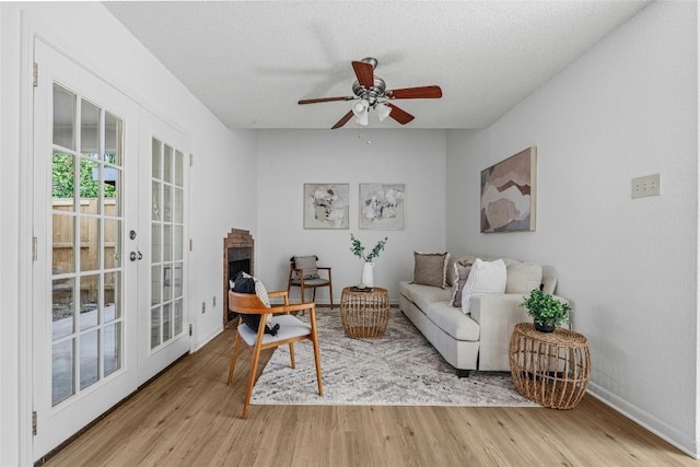 living room with light hardwood / wood-style flooring, french doors, a textured ceiling, and ceiling fan