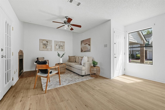 living room featuring light hardwood / wood-style floors, a textured ceiling, and ceiling fan