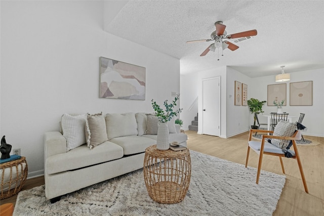 living room featuring a textured ceiling, wood-type flooring, and ceiling fan