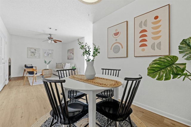 dining area featuring a textured ceiling, wood-type flooring, and ceiling fan