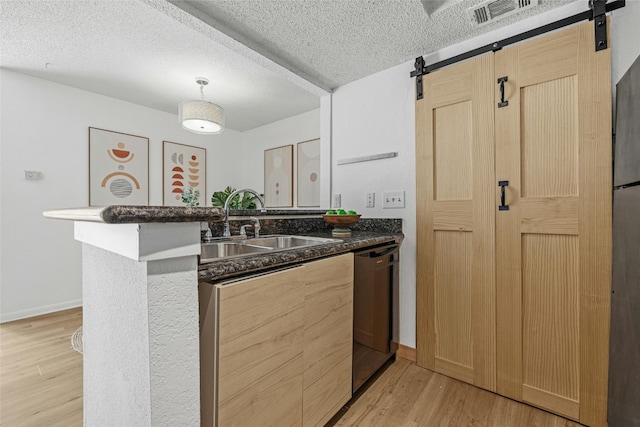 kitchen with dishwasher, a barn door, a textured ceiling, and light wood-type flooring