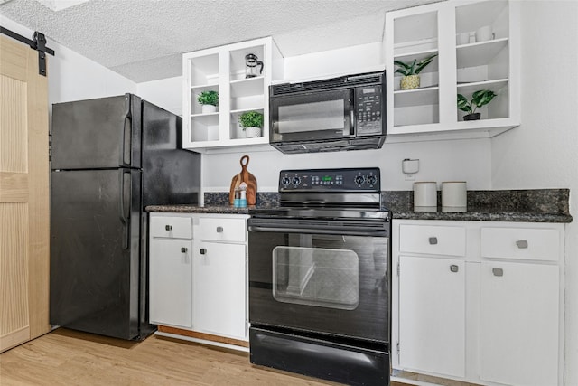 kitchen with white cabinetry, light hardwood / wood-style floors, black appliances, and a barn door