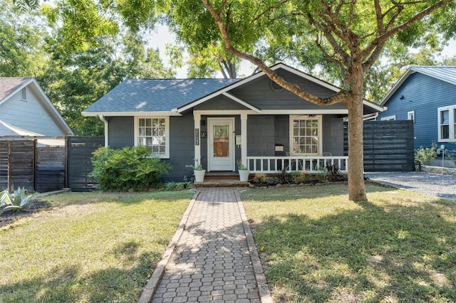 view of front facade with a front yard, covered porch, and fence