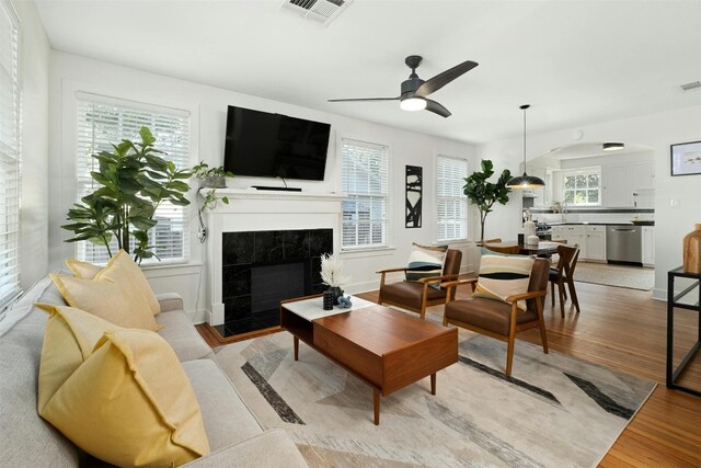 living room with a fireplace, light hardwood / wood-style floors, and ceiling fan