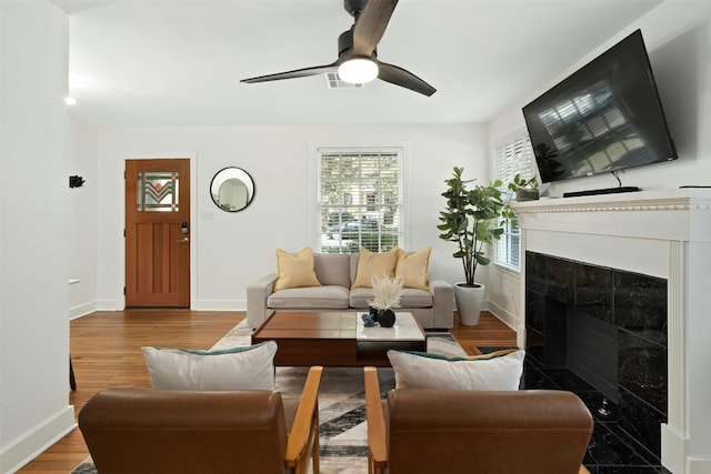 living room featuring light wood-type flooring, visible vents, a fireplace, and baseboards