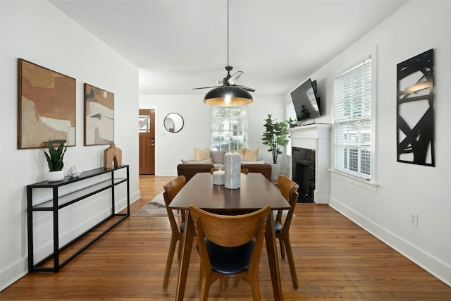 dining space with a fireplace, hardwood / wood-style flooring, and baseboards