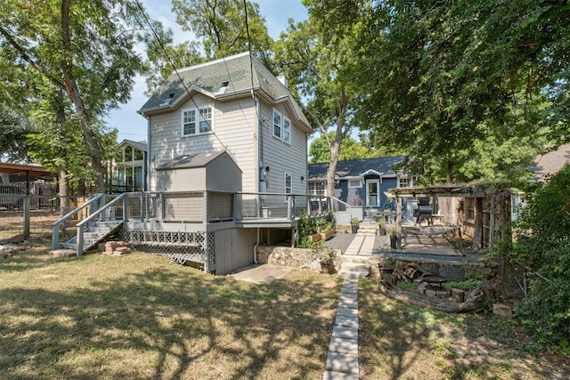 rear view of house featuring stairs, a deck, and a lawn