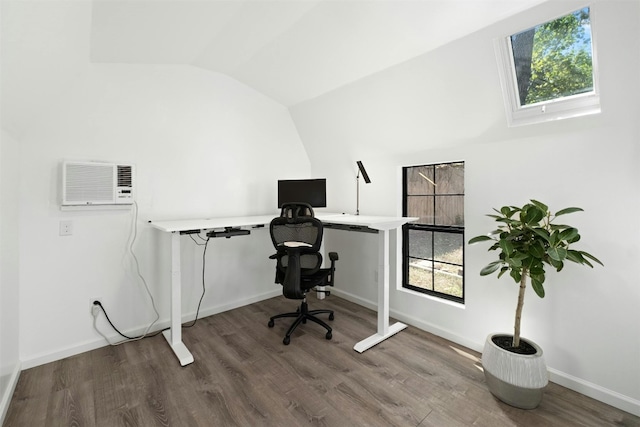 office area with an AC wall unit, vaulted ceiling, baseboards, and wood finished floors