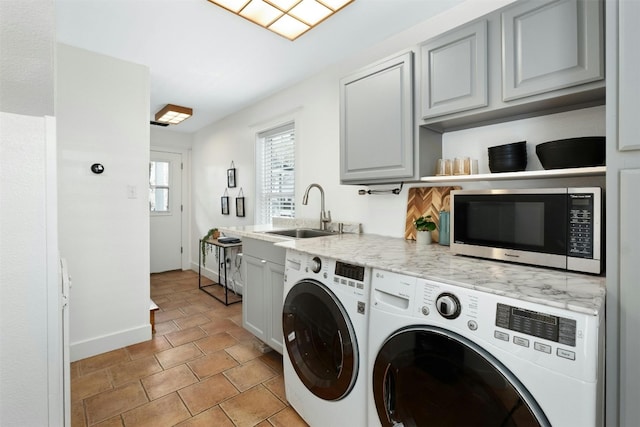 laundry room with cabinet space, baseboards, separate washer and dryer, and a sink