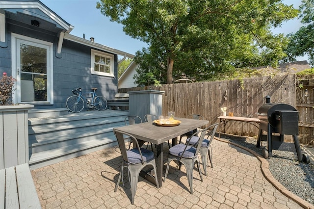 view of patio with outdoor dining space, fence, a fire pit, and grilling area