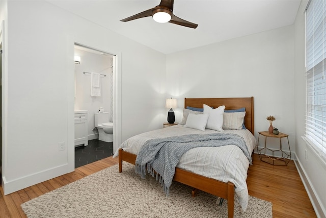 bedroom with a ceiling fan, ensuite bathroom, baseboards, and wood finished floors