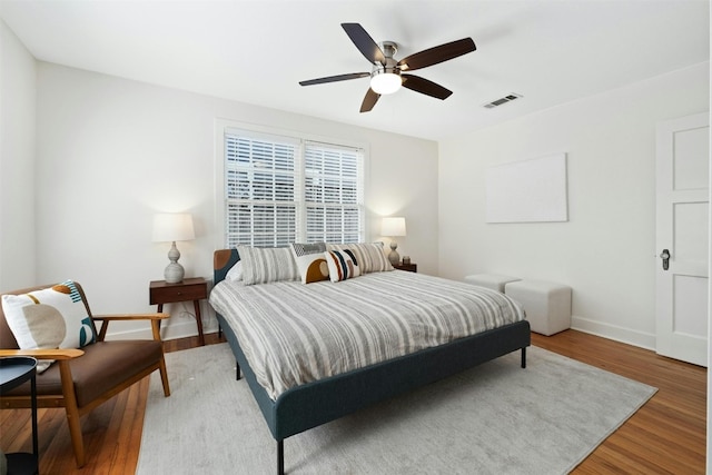 bedroom featuring baseboards, visible vents, ceiling fan, and wood finished floors