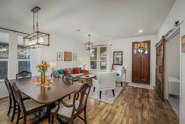 dining space featuring a chandelier, wood-type flooring, and a barn door