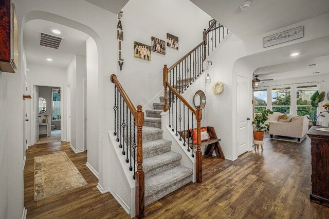 stairs with wood-type flooring and ceiling fan