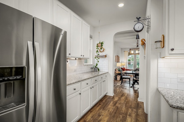 kitchen with dark hardwood / wood-style flooring, backsplash, white cabinetry, stainless steel fridge with ice dispenser, and light stone counters